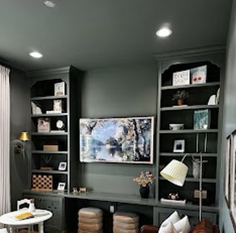 Dark green custom built-in bookshelves around a wall-mounted TV